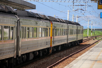 Obraz premium Regional Taiwan Railways train arriving at platform 5 of Fuli Station in Hualien under a bright blue sky with station canopy, signage, tracks and green mountains, highlighting modern rural transportat