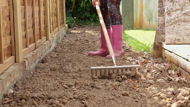 Unidentifiable gardener raking the soil in a flower bed.  Slow motion shot. Push in shot