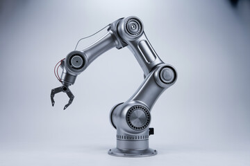 A silver robotic arm with a claw on a light gray background in a studio setting with soft lighting