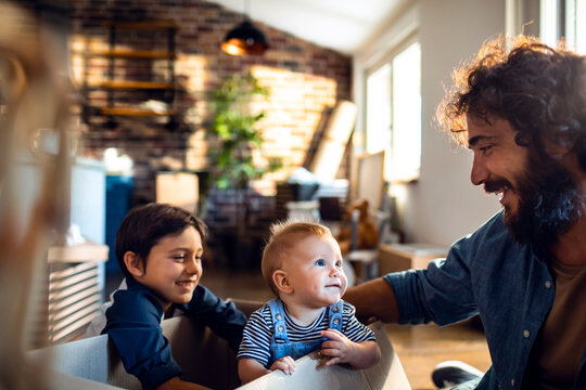 Young father playing with his daughter and son after moving in their new apartment