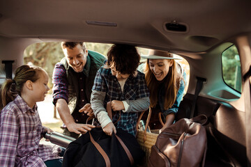 Family packing car trunk for road trip with kids outdoors