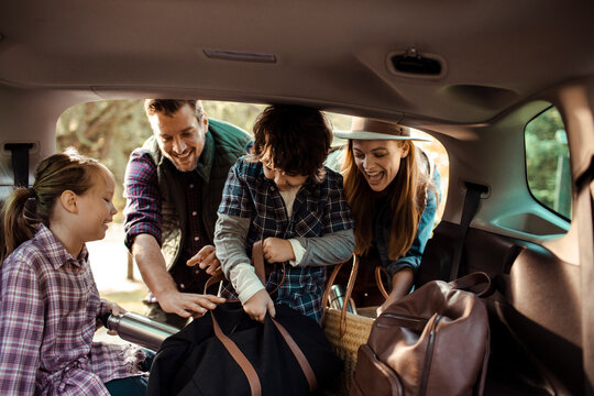 Family packing car trunk for road trip with kids outdoors - Powered by Adobe