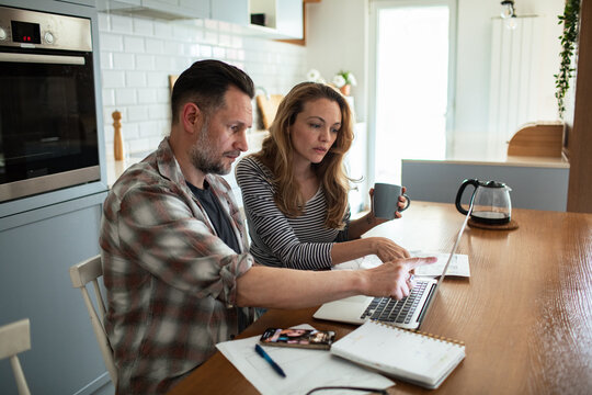 Stressed couple reviewing bills and finances at kitchen table