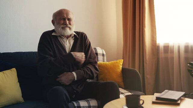 Aged man suffering strong abdominal pain on couch, indigestion or stomach issue
