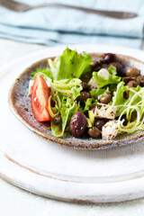 Healthy and tasty salad with feta cheese, various tomatoes, olives, cucumber, onion and lettuce.	