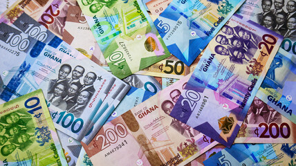 Close up shot of variety of Ghanaian cedi notes denominations spread entirely on surface screen. Colorful Paper money currency as full screen wallpaper background