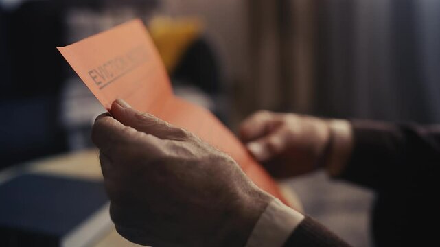 Close-up of senior man opening letter, stressed over eviction notice and debts