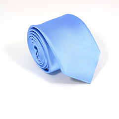 A plain blue tie rolled isolated on white background closeup view 