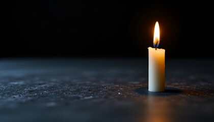 a single lit candle on a black surface with the flame in sharp focus