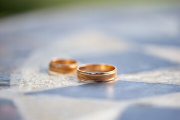 Close-Up of Two Gold Wedding Rings on a Textured Surface..