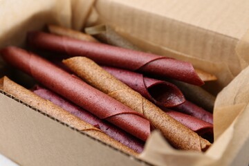 Tasty fruit leather rolls in cardboard box, closeup