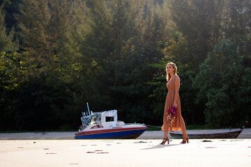 Woman Walking on a Beach Carrying Flowers Near Moored Boats..