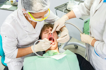 Teenager undergoes dental procedures in a bright clinic with professionals attending to oral health needs