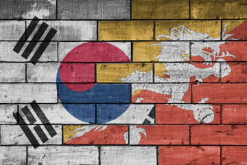 Fototapeta premium colourful painted big national flag of south korea and flag of bhutan on a massive old brick wall background. concept