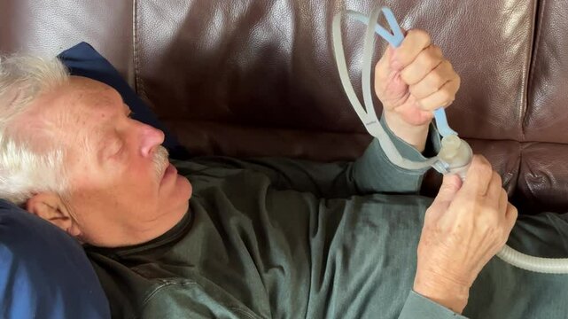 Senior man on sofa adjusts his CPAP 