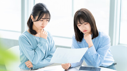 資料を見ながら考える2人の女性・ビジネスウーマン