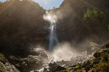 A roaring alpine waterfall crashes over cliffs surrounded by spring bloom. This is Engstligenfälle...