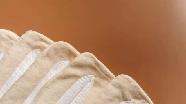 Close-up of several neatly stacked reusable fabric diapers with white accents, arranged on a warm brown background in a natural setting.