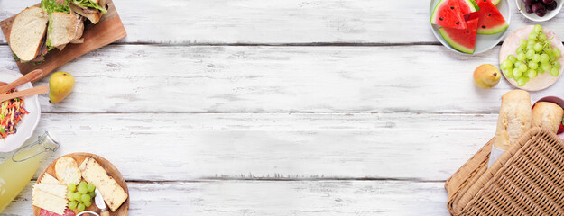 Summer picnic food double border. Top view over a white wood banner background. Picnic basket, fruit, salad, sandwiches and snacks. Copy space.