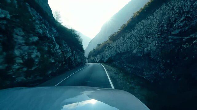 Empty curved mountain road winds through misty valley between towering rocky cliffs. The serpentine asphalt path creates dramatic perspective leading into atmospheric distance.