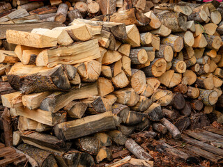 A stack of logs with some grass in between them. The image has a calm and tranquil atmosphere, with the grass providing a natural contrast to the rough texture of the logs. Pile of firewood.