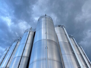 Large stack of silvery tanks with a cloudy sky in the background