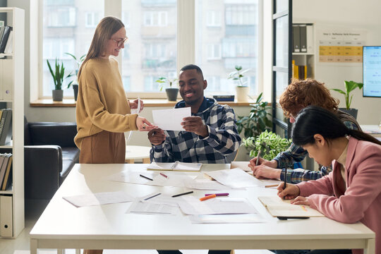 Diverse group of students in classroom environment engaged in studying foreign languages, collaborating and sharing learning materials. Bright and spacious room enhancing learning experience