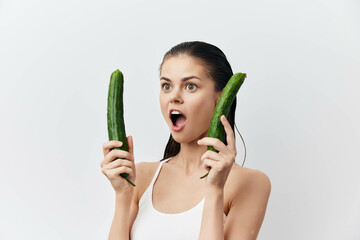 surprised woman holding cucumbers, bright background, emotional expression, healthy lifestyle, fresh produce, concept of nutrition and self care