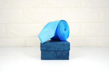 A blue tie rolled on gift box closeup view 