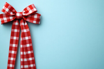 a red gingham plaid ribbon bow tied vector on soft light blue background, clean and minimalistic banner design with space. Festive/Holiday Decoration.