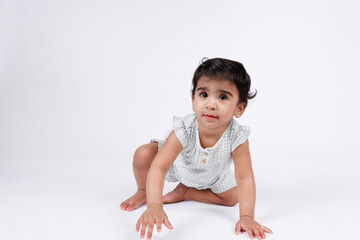 Portrait of cute happy little baby girl crawling wearing white dress isolated on white background