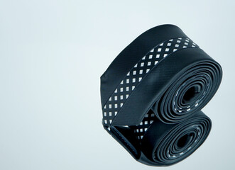 A black tie rolled over glassy reflection surface closeup view 