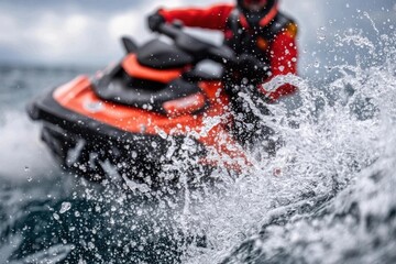 Fototapeta premium Orange watercraft sprays water, a person in red drives it on the ocean, creating splashes and wave.