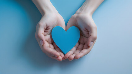Obraz premium Hands gently holding a blue heart symbol on a light blue background, representing care, love, health awareness, and support 