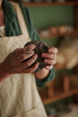 Master of ceramics in the process of work. Natural clay. The hands of a clay sculpting master. The process of kneading clay. Removing air bubbles and improving clay plasticity. Vertical photo.