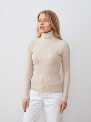 Model poses in stylish studio setting wearing a fashionable turtleneck sweater