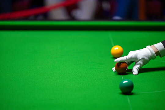 A snooker referee places balls on the table with pinpoint accuracy