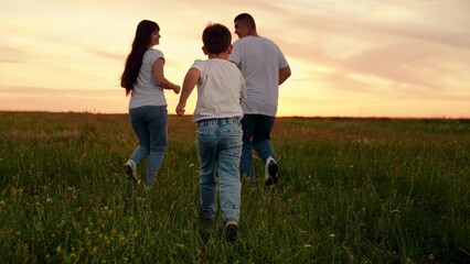 Happy family team, children, parents, run together in green meadow. Family game father mother, child son fun running. Child, parents dream, mom dad children in nature. Weekend play, holiday picnic