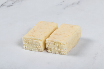 Cottage cheese coconut dessert bar in white chocolate glaze. White background. Close-up	