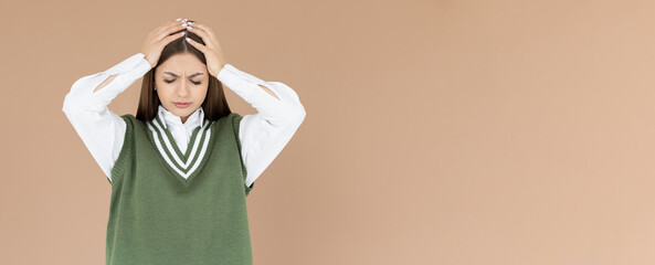 Woman with hard headache holding hands on head. Young woman touching her temples feeling stress, on brown background. Woman suffering from headache. In school uniform