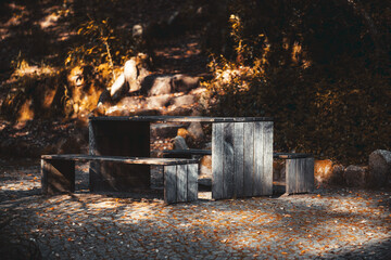 Moody low-key shot of a rustic wooden picnic table and benches on a cobblestone clearing in a...