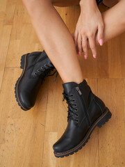 Elegant woman showcasing fashionable black boots in a stylish indoor setting