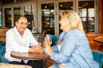 A beautiful plump woman sits at a cafe table with her middle-aged husband during their romantic date.