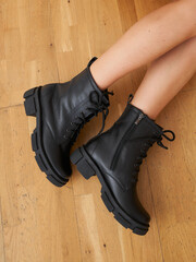 Fashionable black boots complement slim legs in a stylish interior setting