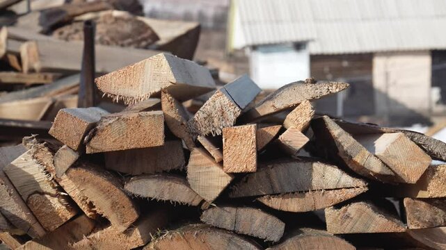 Working lumberjack systematically throwing freshly split firewood on to growing woodpile, preparing essential winter fuel supply with traditional manual labor techniques. Close up view