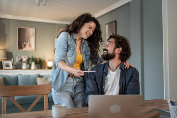 Happy couple celebrating positive pregnancy test result at home