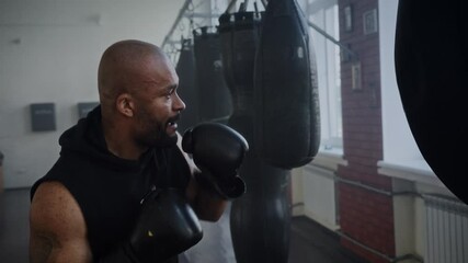 Focused African American man boxer beats heavy punching training - Powered by Adobe
