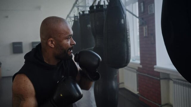 Focused African American man boxer beats heavy punching training - Powered by Adobe