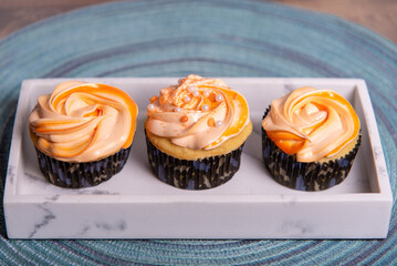 Three orange cream cupcakes on a plate