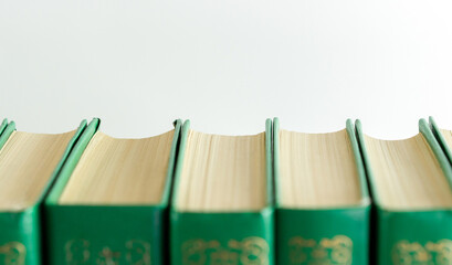 Collection of green books lined up on a shelf against a light background showcasing their spines...